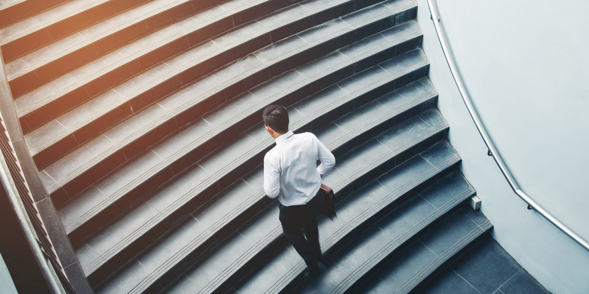 imec-magazine-2018-september-05-startupsgrownups Man in a white shirt climbing a wide staircase with a metal handrail