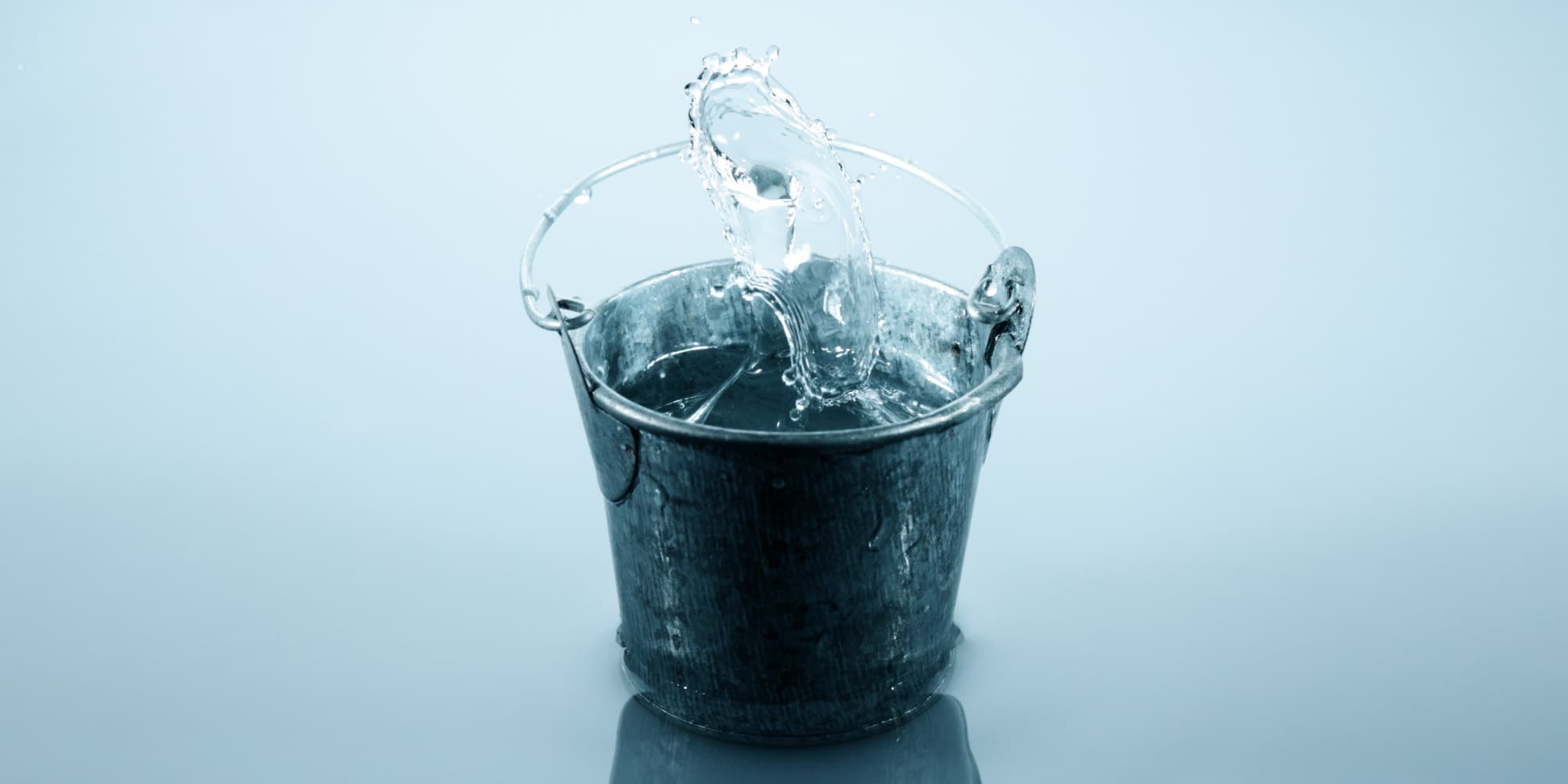 imec-magazine-2018-september-06-burnout_1 Water dat in een metalen emmer spat tegen een lichtblauwe achtergrond