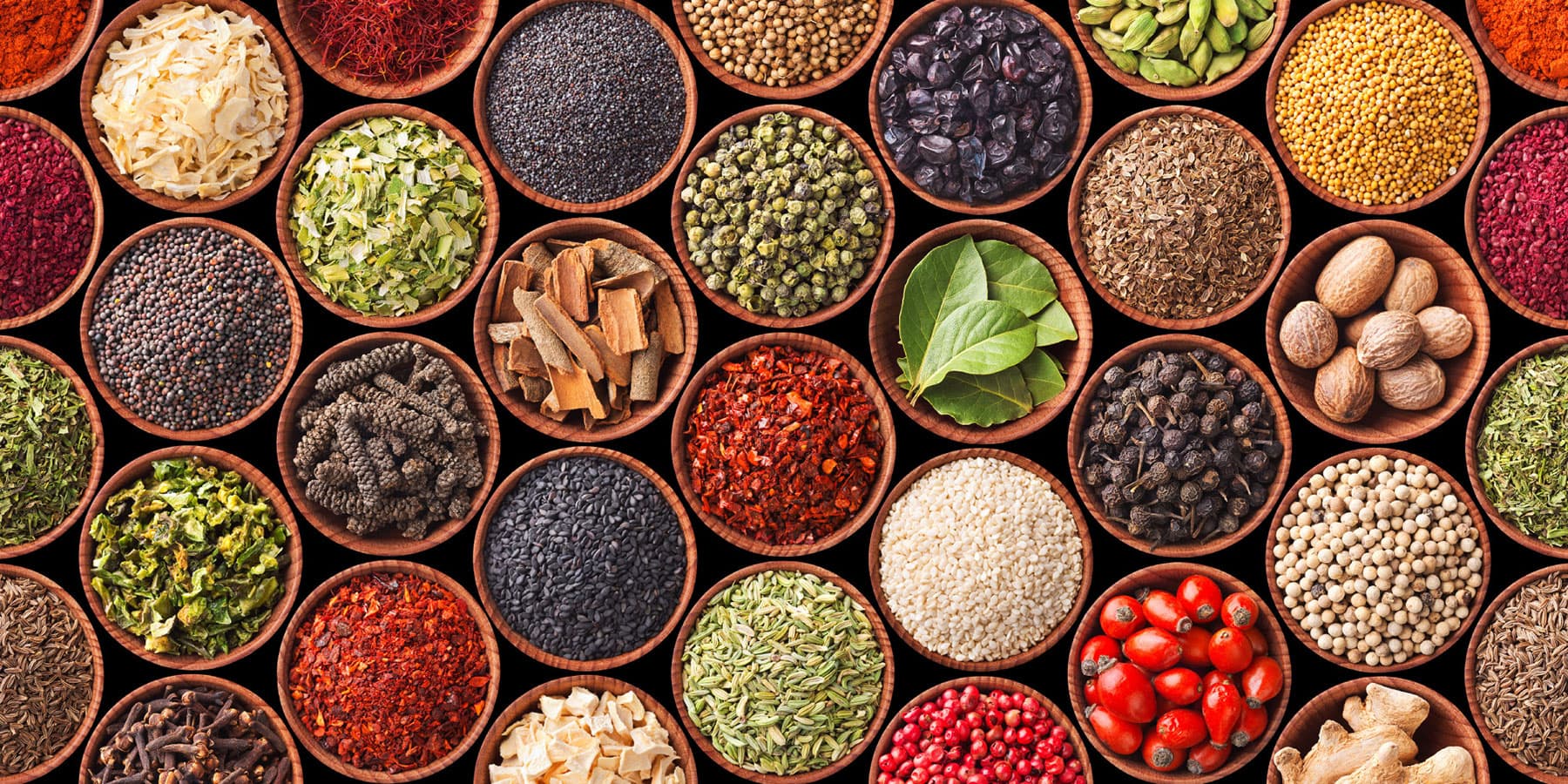 imec-magazine-8-smart-food_1 Assorted spices, seeds and dried herbs arranged in round wooden bowls on a black background