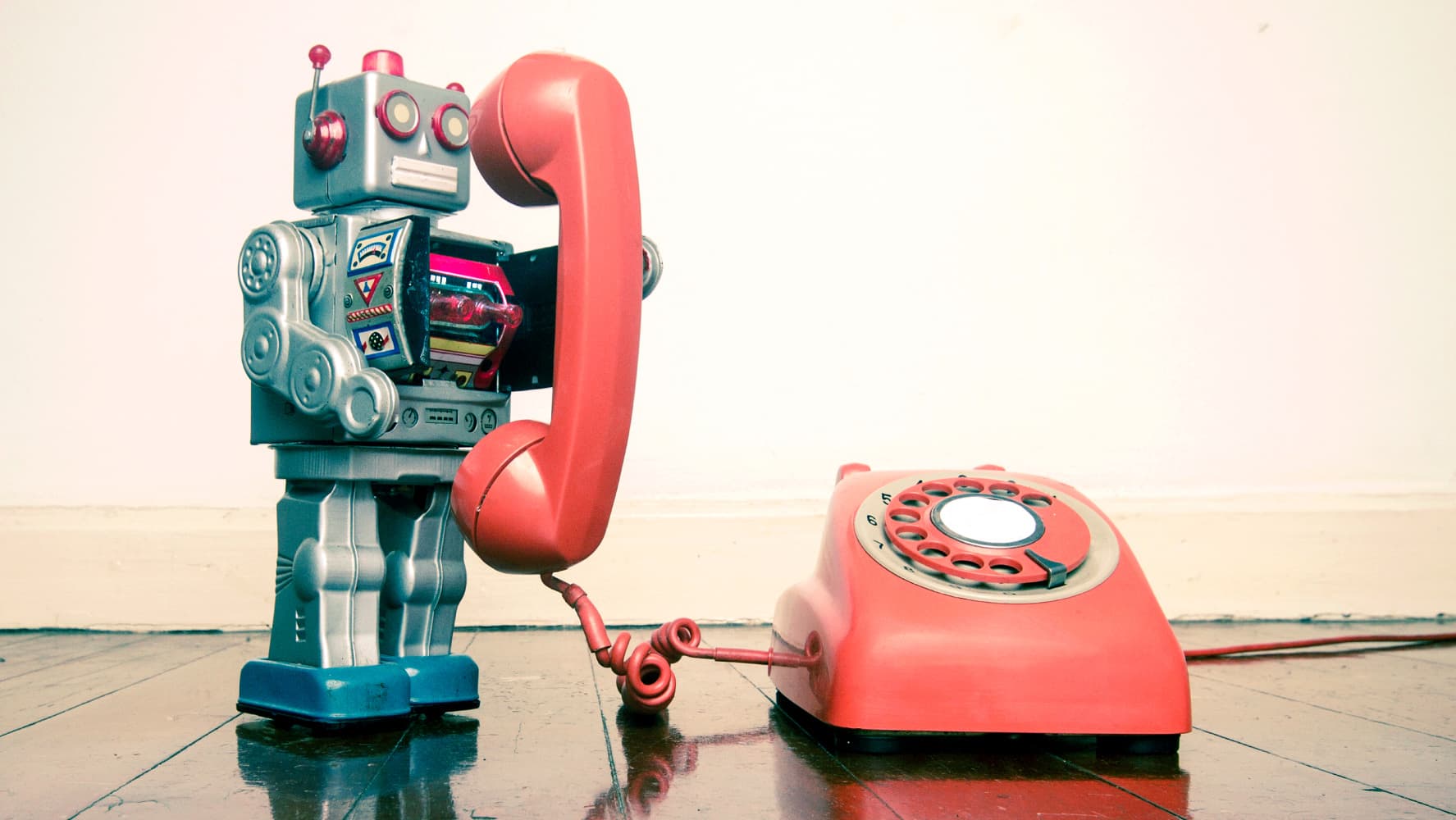 imec-magazine-ai-special-06_humanlikeai_torenbabel_1 Toy robot holding a red rotary phone receiver beside the matching phone base