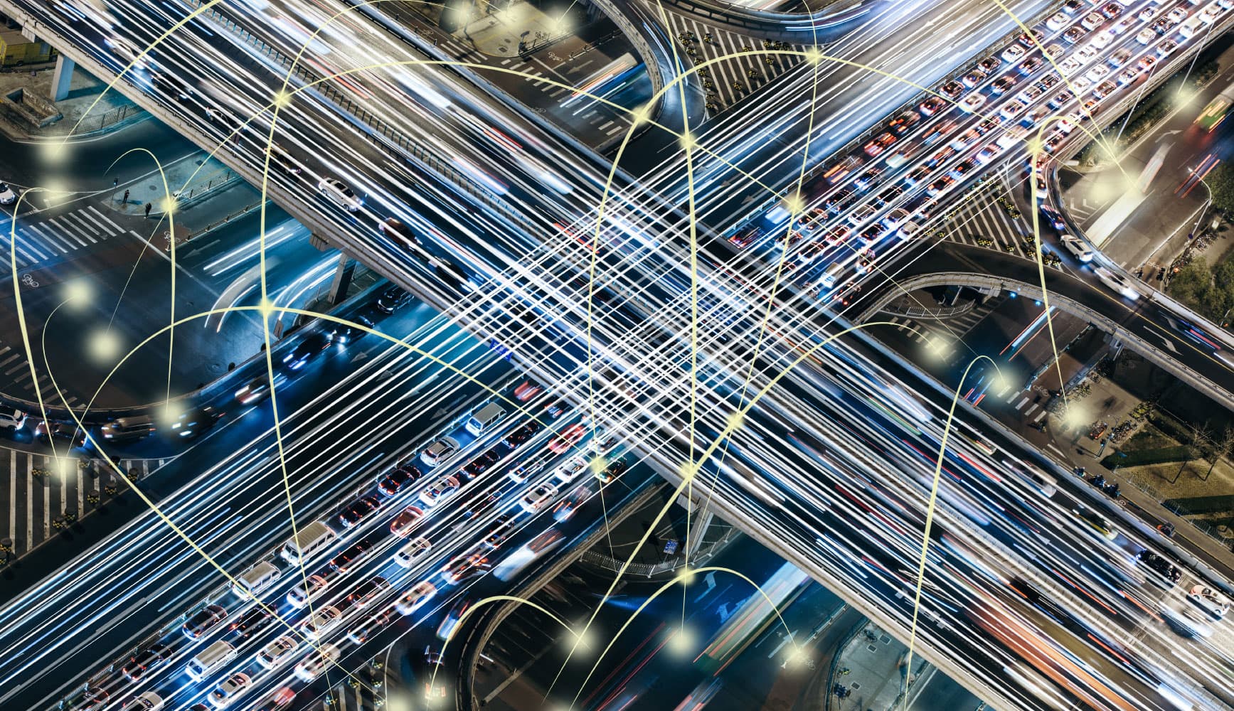 imec-magazine-ai-special-19_smart-highway_1 Aerial view of a busy highway interchange with light trails and connected cars overlaid