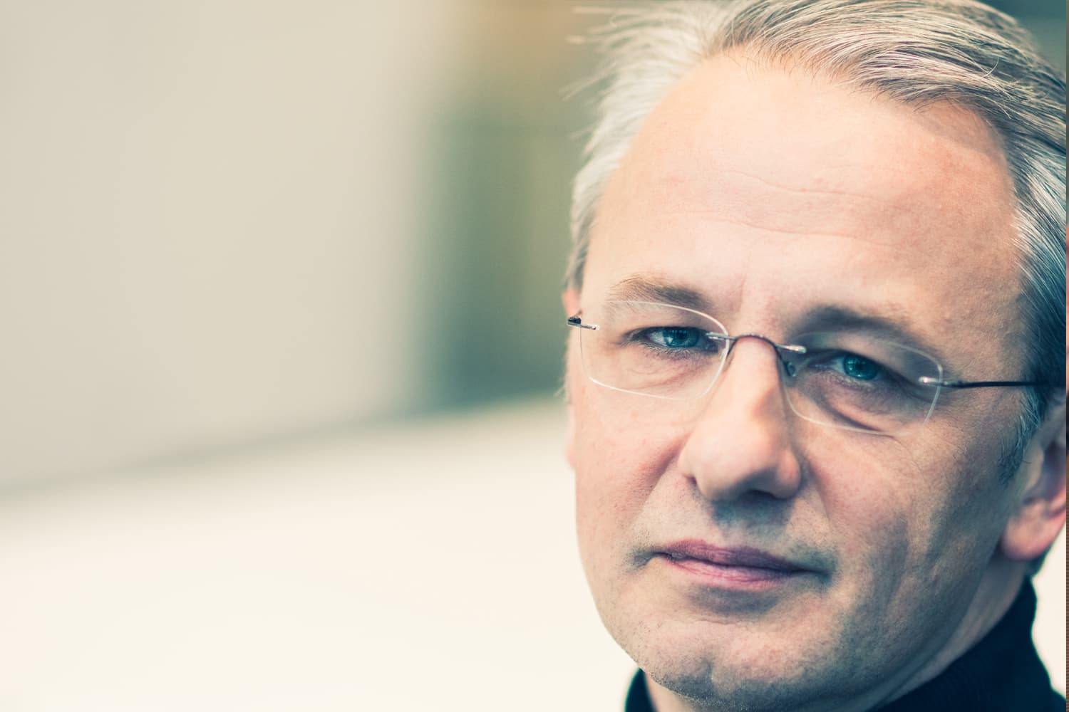 imec-magazine-c-01-john-baekelmans_1 Close-up portrait of John Baekelmans wearing glasses, against a soft blurred background