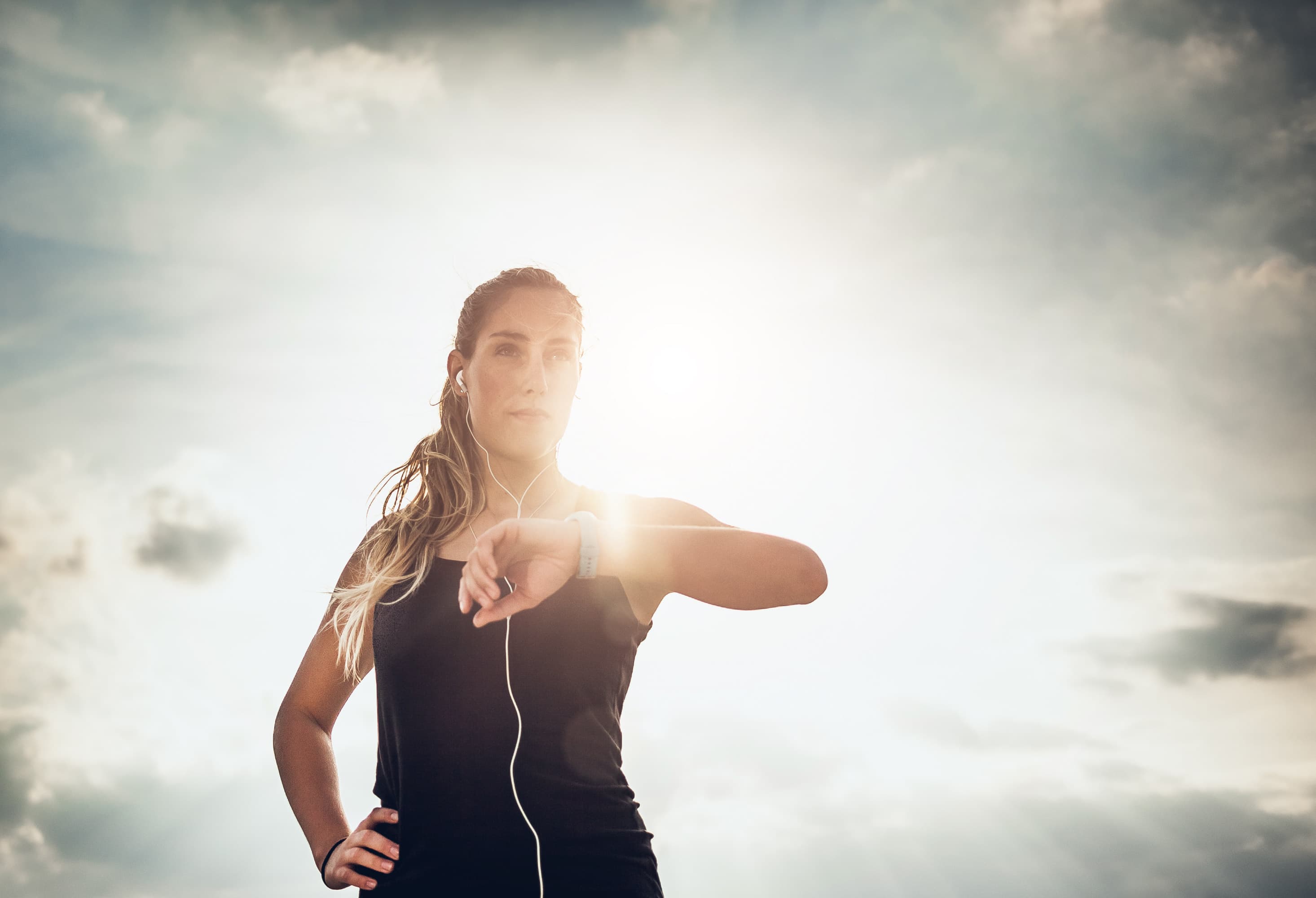 imec-magazine-digimeter-health_1 Woman outdoors checking a fitness tracker on her wrist while wearing earphones