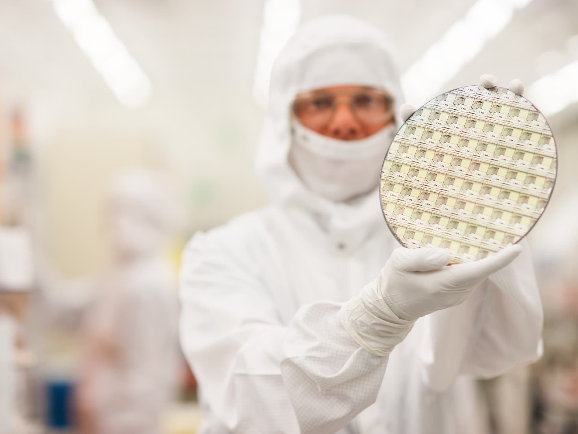imec-magazine-GAN-SOI_1 Cleanroom researcher in protective suit holding a semiconductor wafer up to the camera