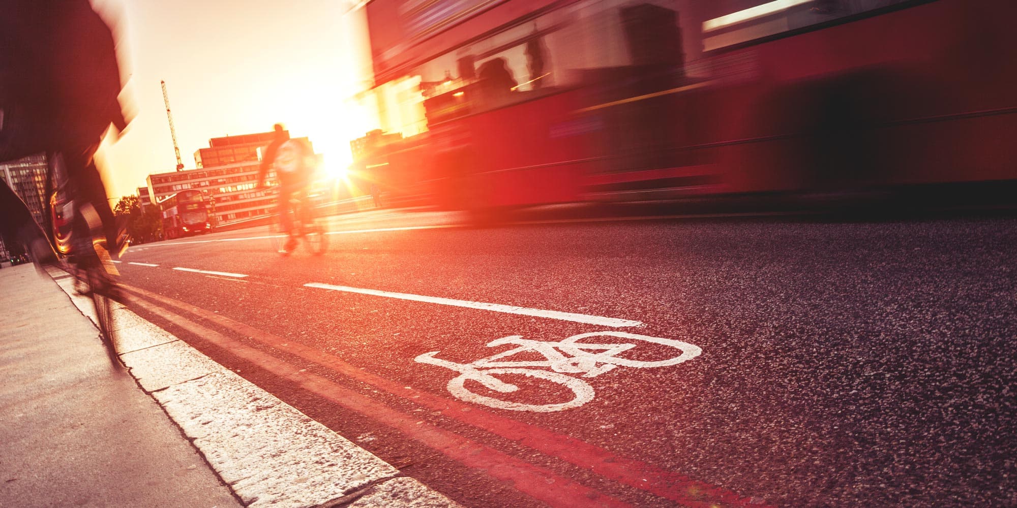 imec-magazine-smart_mobility-header_1 Sunlit city street with a bike lane marking and blurred traffic passing by