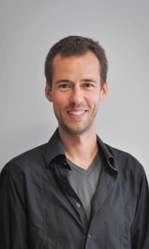 imec-magazine-Tony-van-Rooij-bio_1 Portrait of Tony van Rooij smiling against a gray background