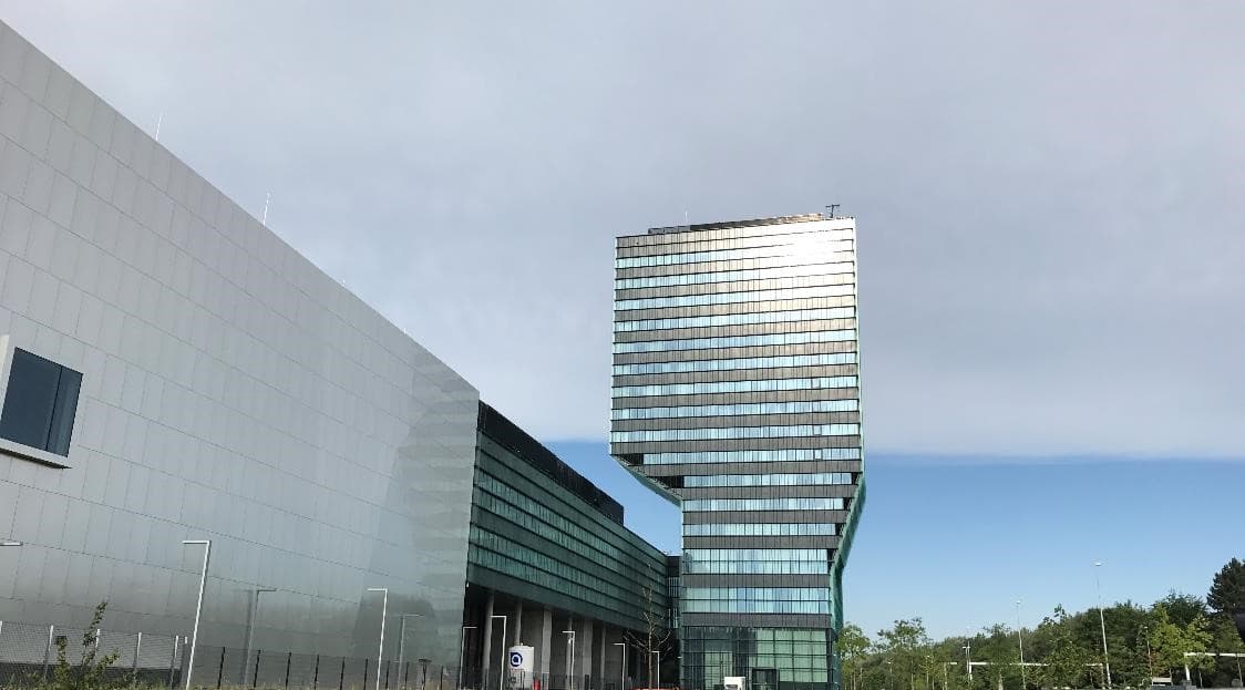 imec-toren_3 imec headquarters building with a tall glass tower under a cloudy sky