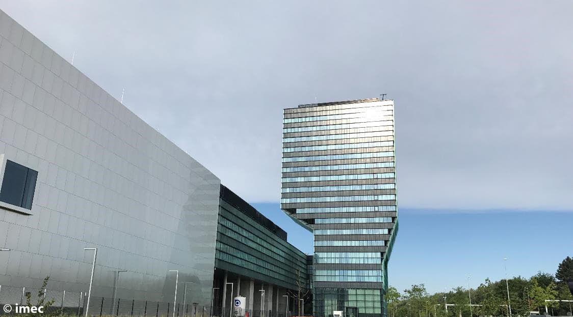 imec-toren_4 imec campus building with a distinctive glass tower under a cloudy sky