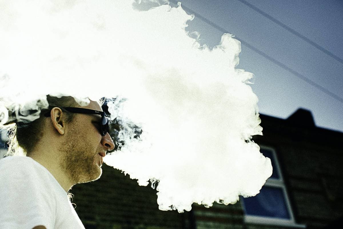 ImecCityofThings_AirQuality2 Man met een zonnebril die buiten een grote wolk damp uitblaast