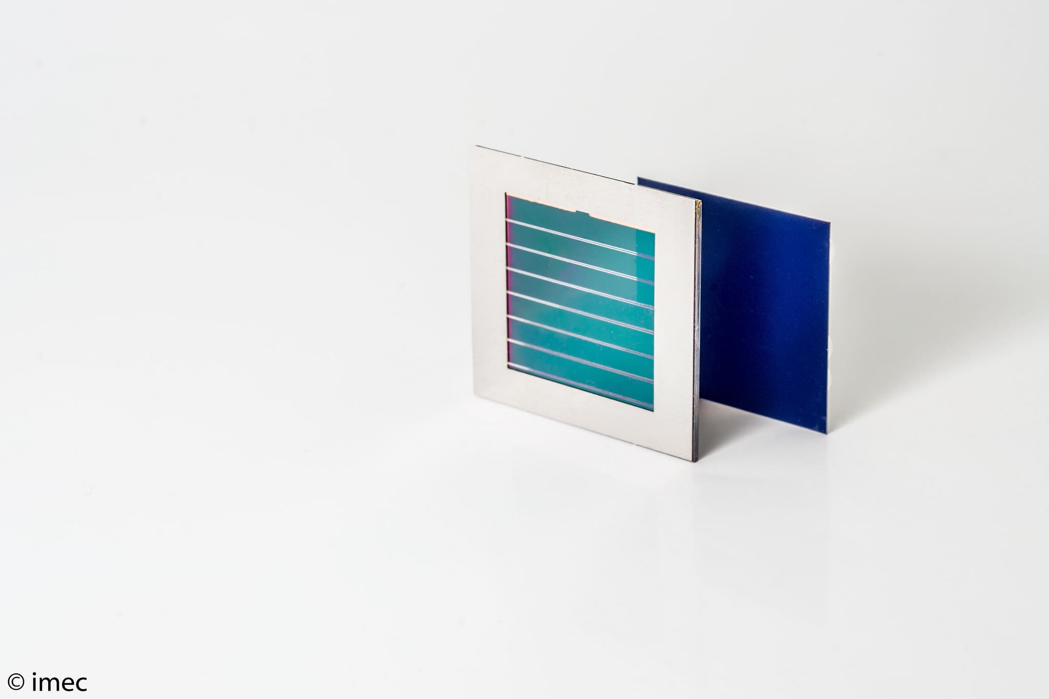 imecperovskiteSitandem_lowres_0 Perovskite-silicon solar module with layered blue and teal cells on a white background