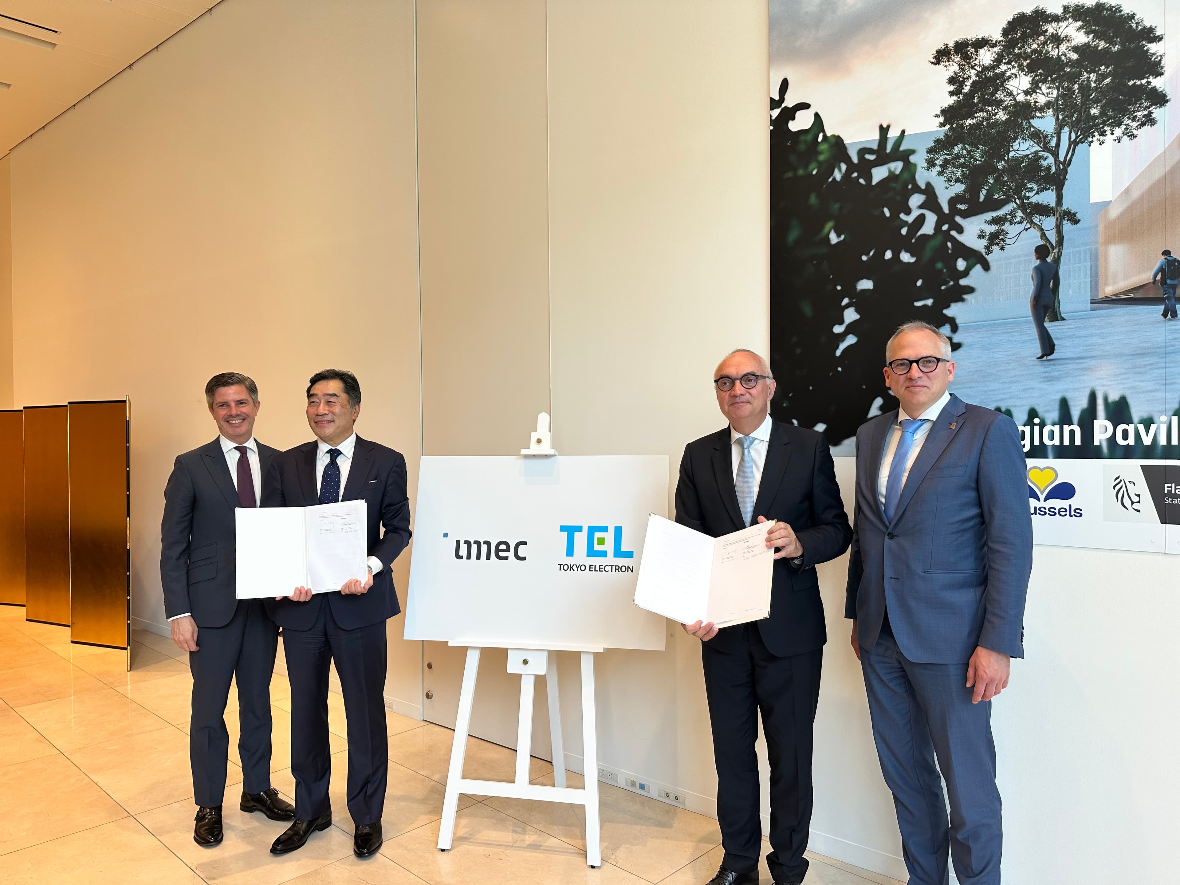 IMG_2885_0 Vier functionarissen poseren met ondertekende mappen naast een imec- en Tokyo Electron-bord tijdens de partnerschapsceremonie.