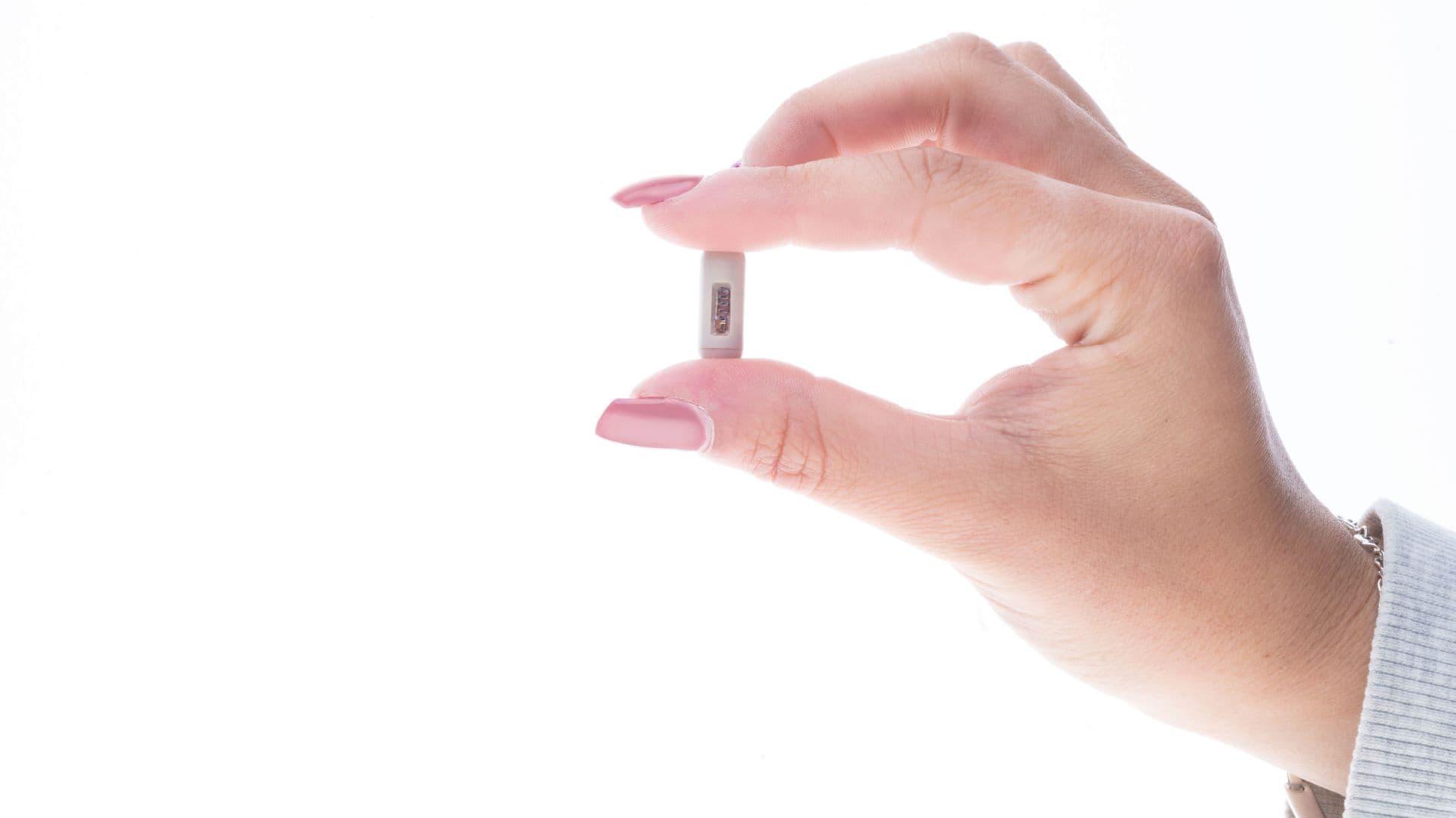 Ingestible Hand holding a small ingestible sensor prototype between thumb and forefinger