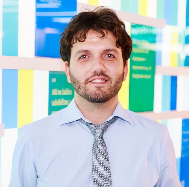 ioannis2_1 Portrait of Ioannis Tsanakas in a light blue shirt and tie against a colorful glass wall