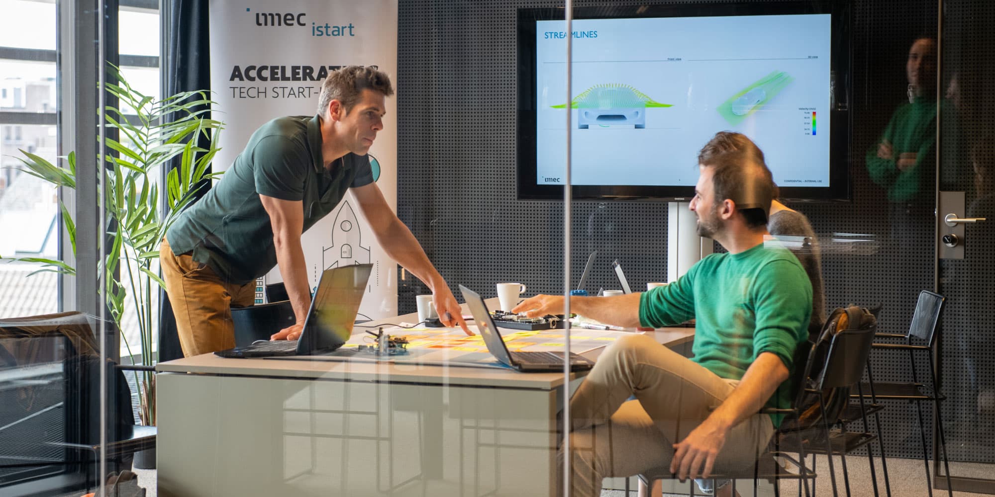 istart People collaborating in an imec iStart meeting room with laptops and a presentation screen
