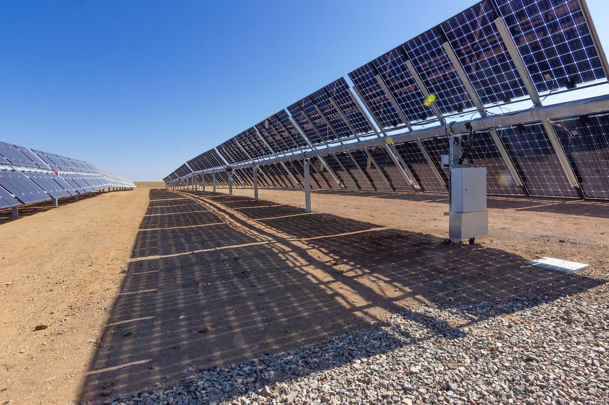 istock-1124875638-solar-cells_1 Rows of solar panels in a solar park casting long shadows on bare ground