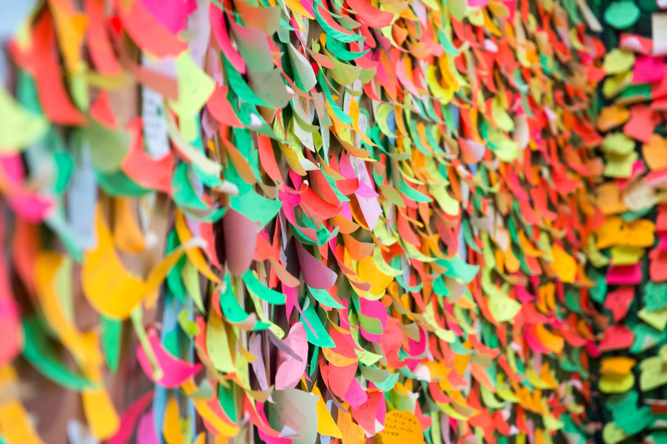 iStock-457741199_0 Wall covered with colorful paper notes and petals in a blurred, vibrant pattern