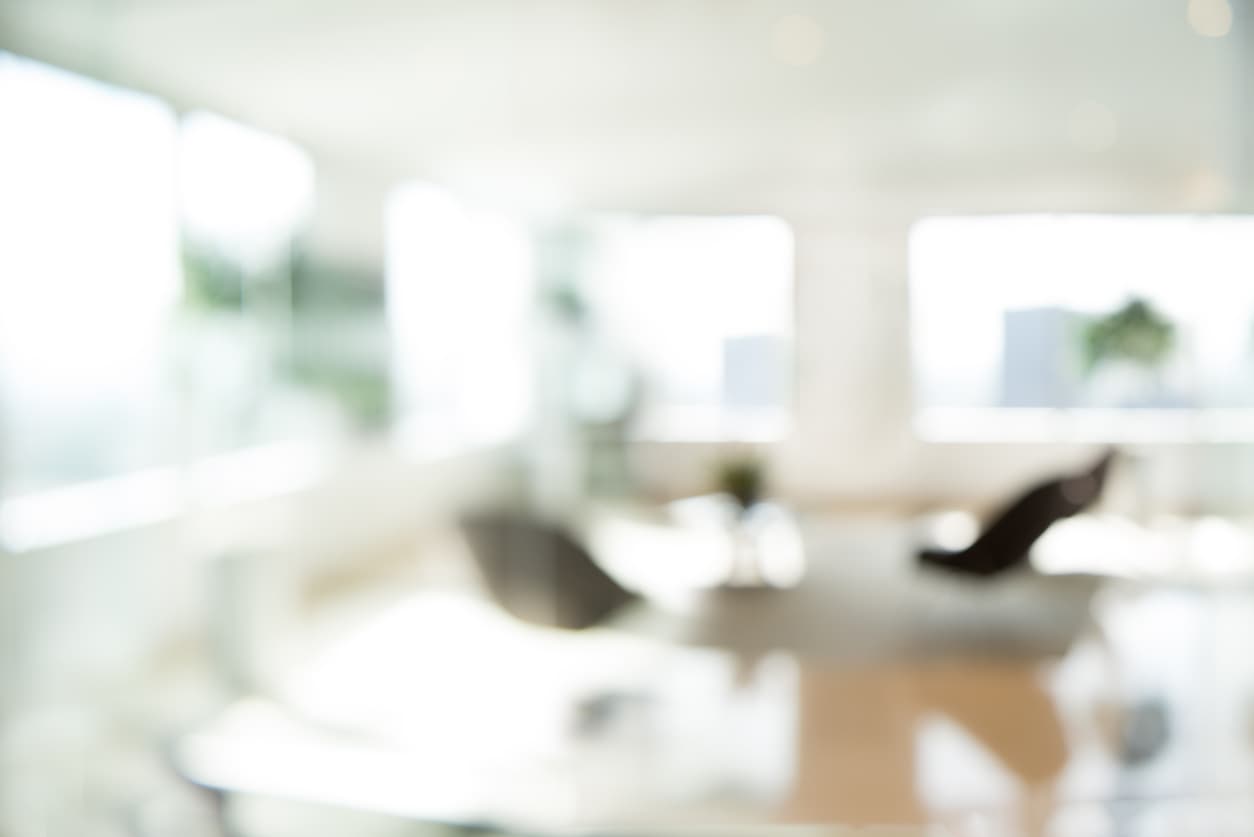 iStock-488908066_1 Blurred modern office interior with chairs, tables, and large windows in soft daylight