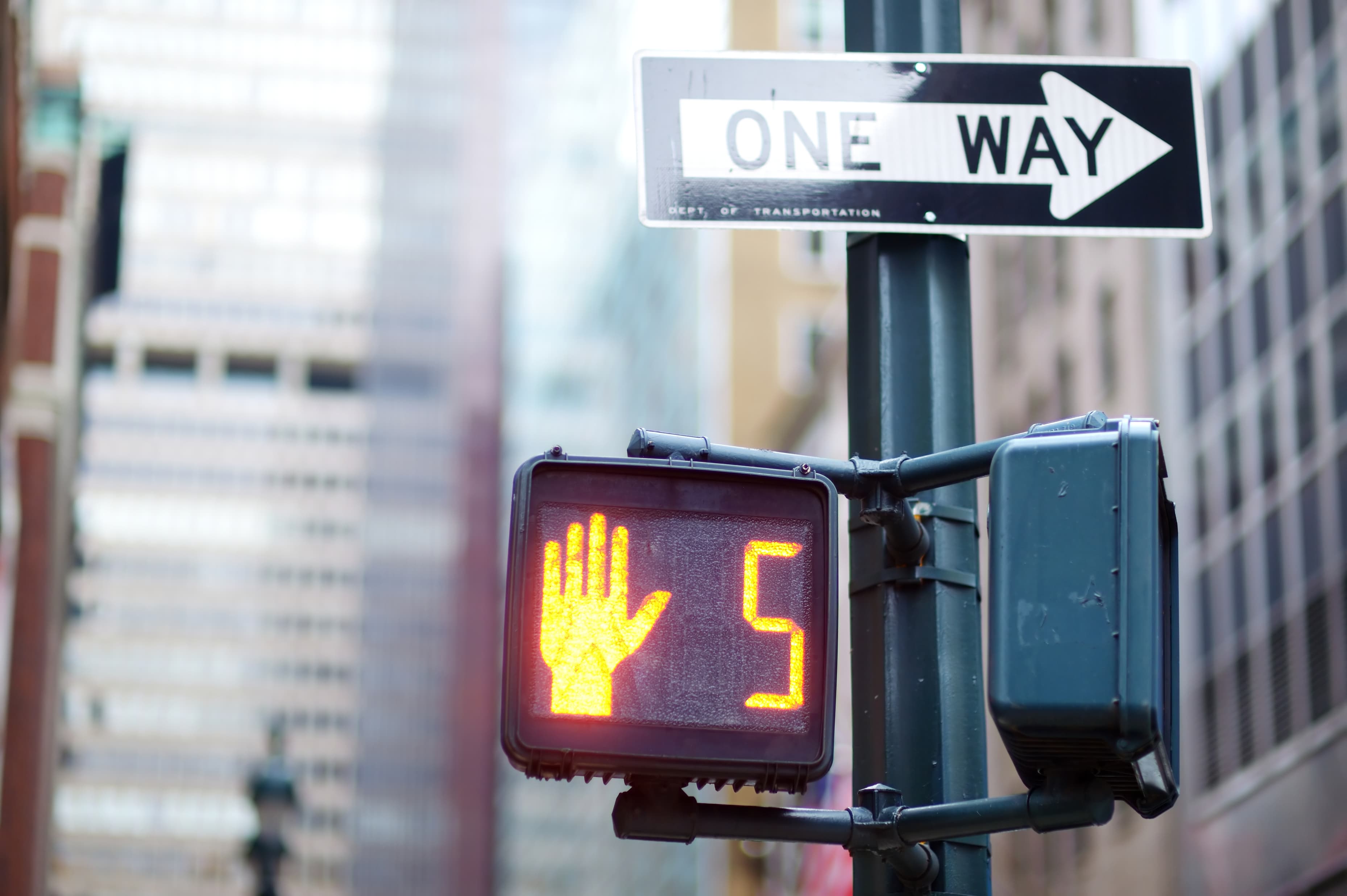 Pedestrian signal and one-way street sign One-way street sign above a pedestrian signal showing a red hand and countdown timer