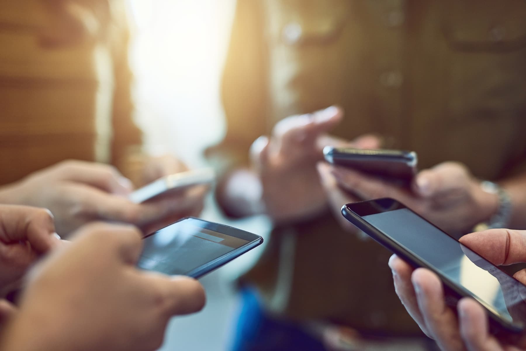 people holding smartphones in group People holding smartphones in a blurred group setting, suggesting mobile connectivity and wireless communication