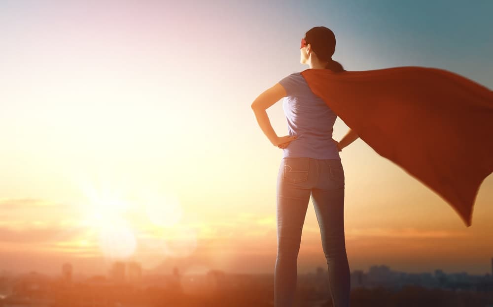 iStock-Superpeople Woman in a cape standing like a superhero against a sunset sky