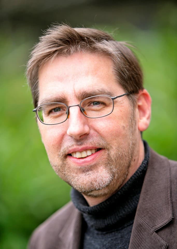 Jef_1 Portrait of Jozef Poortmans wearing glasses against a green outdoor background