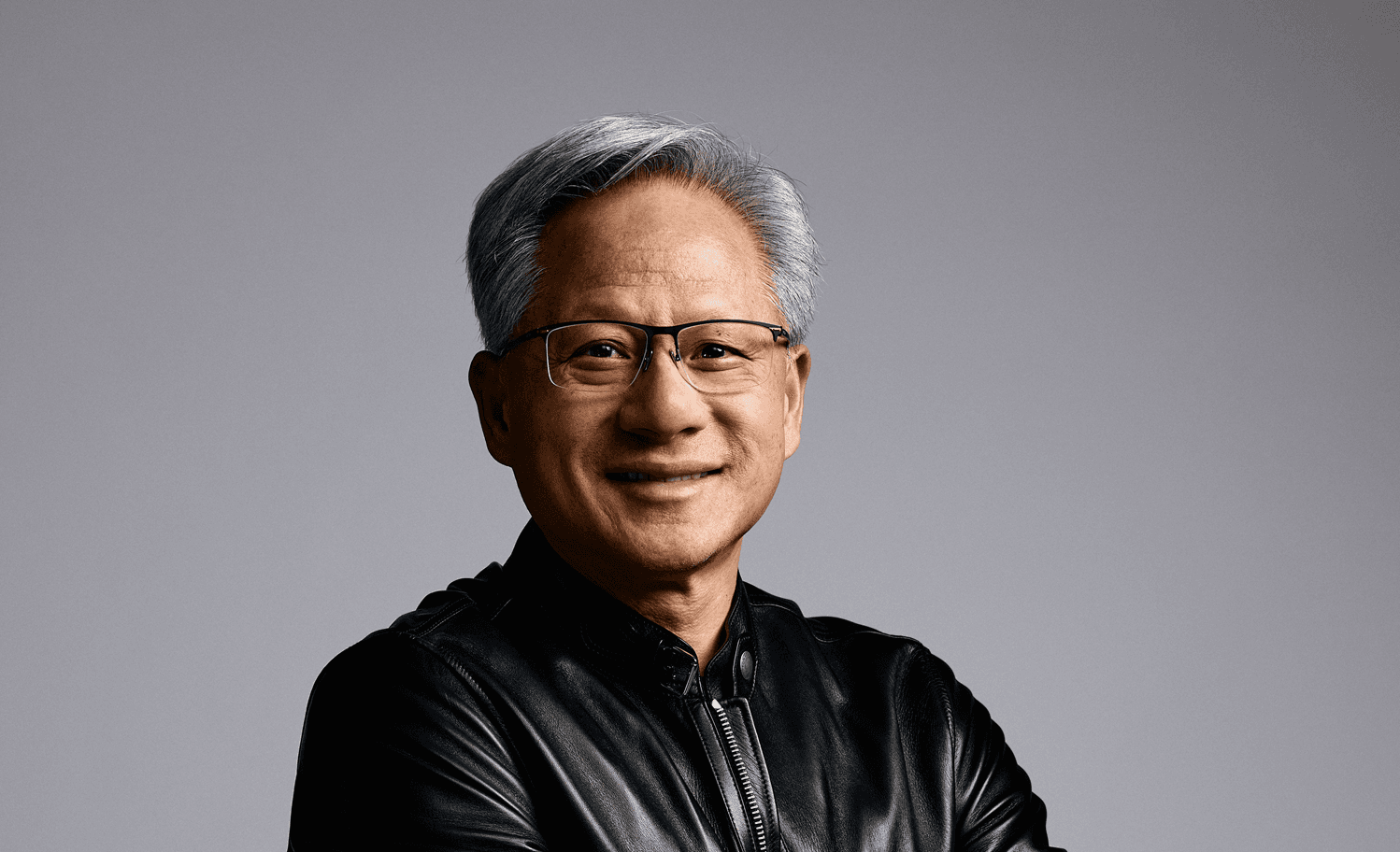 jensen-huang-headshot-gray-background Portrait of Jensen Huang wearing glasses and a black jacket against a gray background
