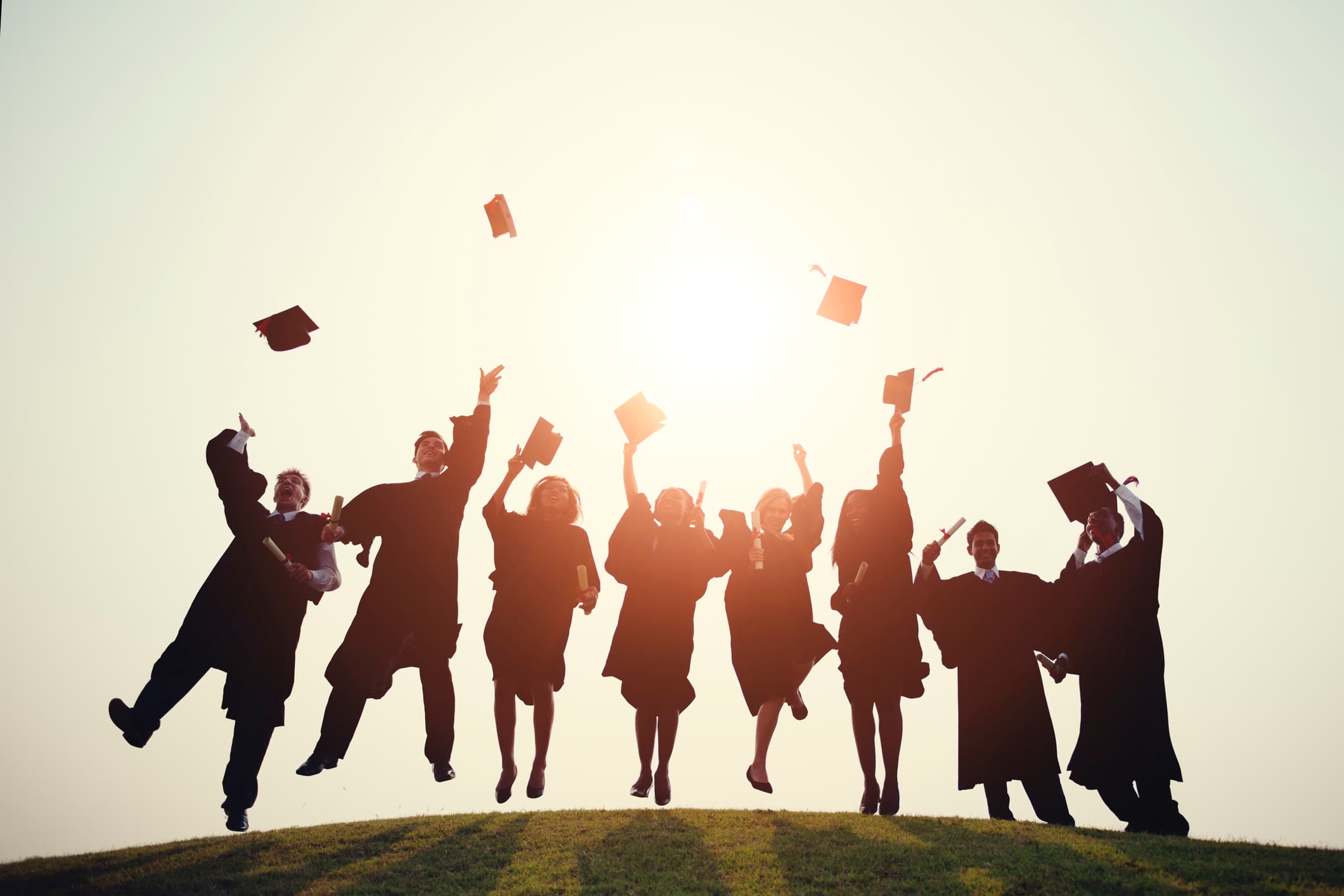 jobfair_1 Graduates in caps and gowns celebrate by throwing their diplomas into the air at sunset.