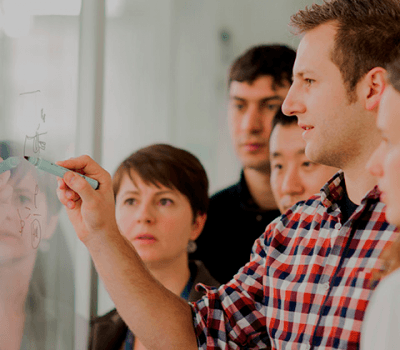 jobs_fitted400x350_1 Researchers collaborating at a whiteboard during a team discussion