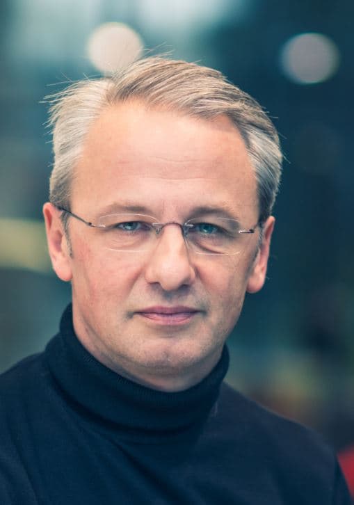 john_baekelmans_1 Portrait of John Baekelmans wearing glasses and a dark turtleneck