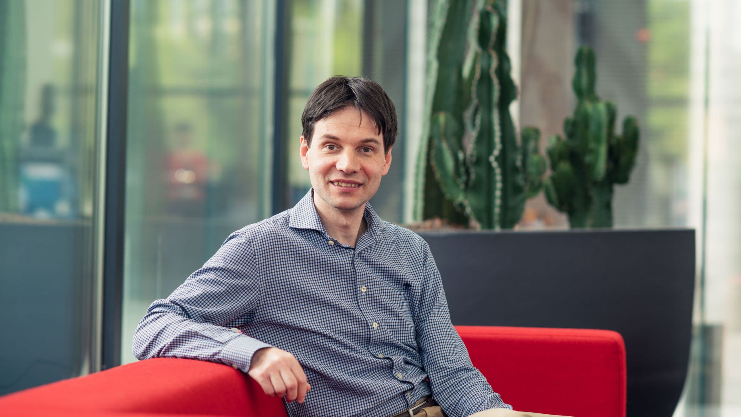 kristof_vaesen_lr_1 Kristof Vaesen seated on a red sofa in a modern office lounge
