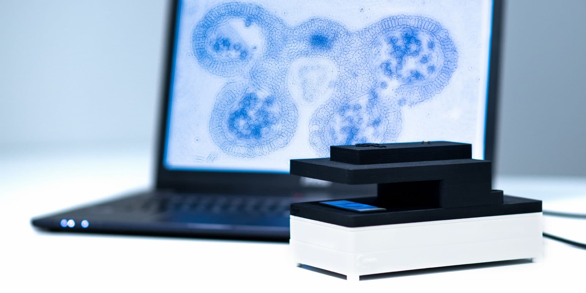 lensfree-imager-kit_1 Compact lens-free microscope demo kit in front of a laptop showing a blue microscopic plant cell image