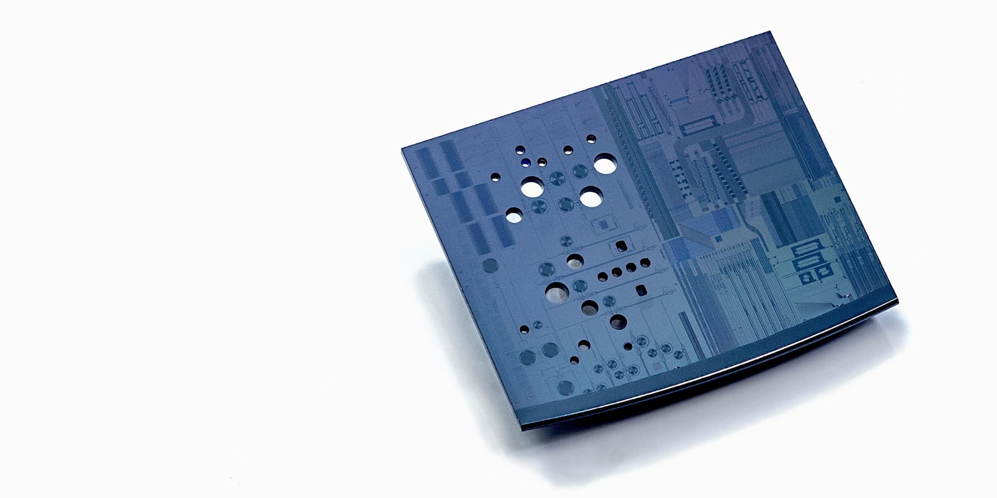 life-sciences-technology-platform-biosensor_1 Blue semiconductor chip with multiple circular openings and circuit patterns on a white background