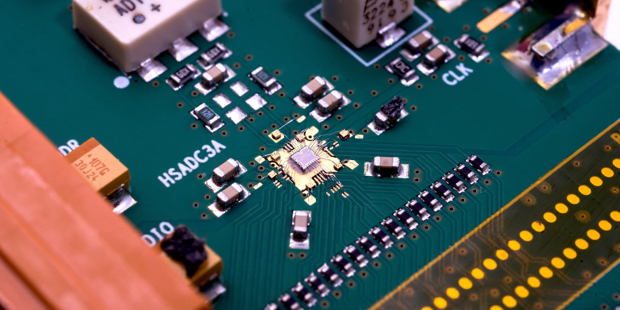 Low-Power-IP-Blocks-for-5G_1 Close-up of a circuit board with a central chip and surrounding electronic components