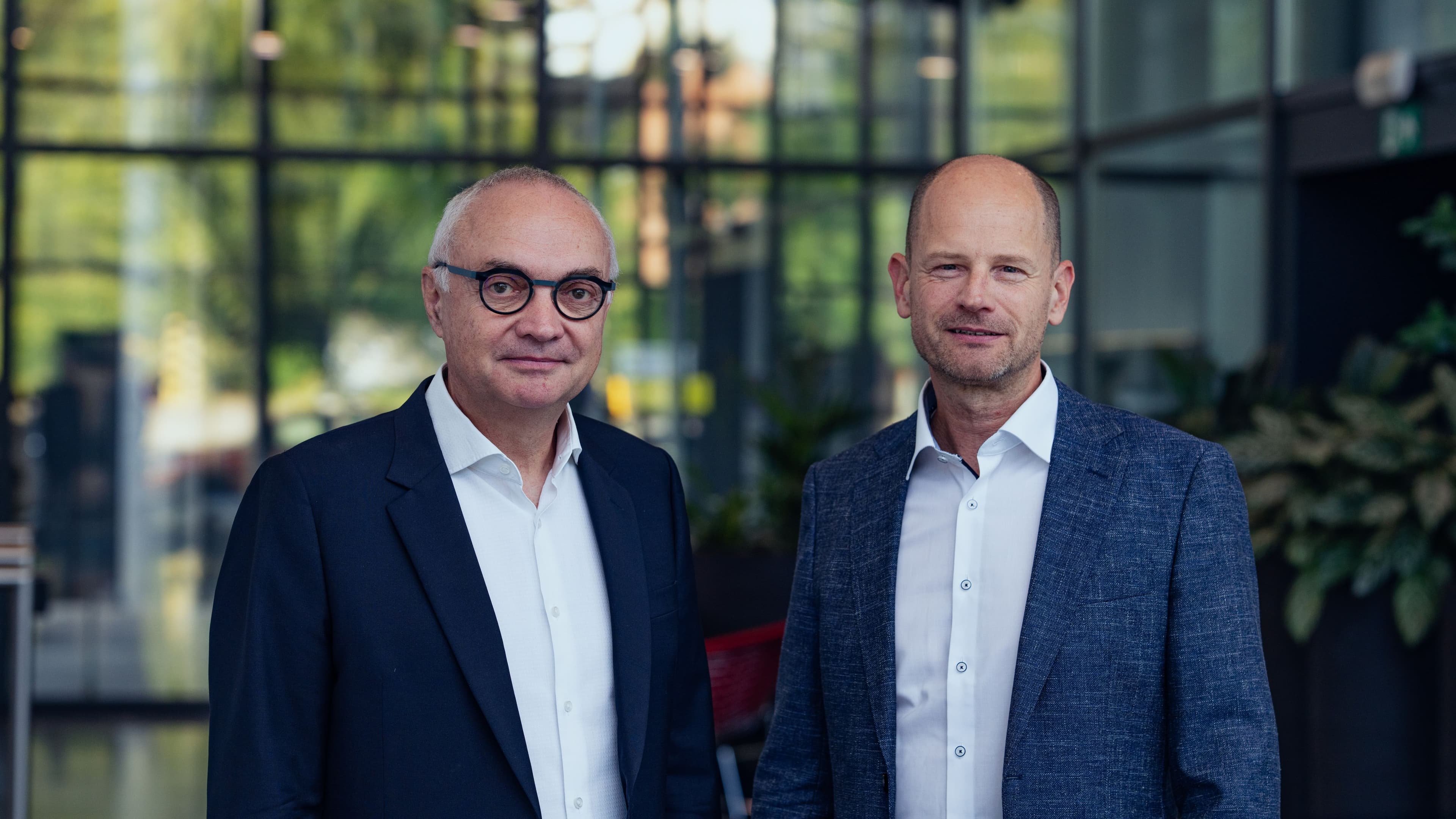 Luc%20en%20Patrick Luc Van den hove and Patrick Vandenameele standing in front of a modern glass building