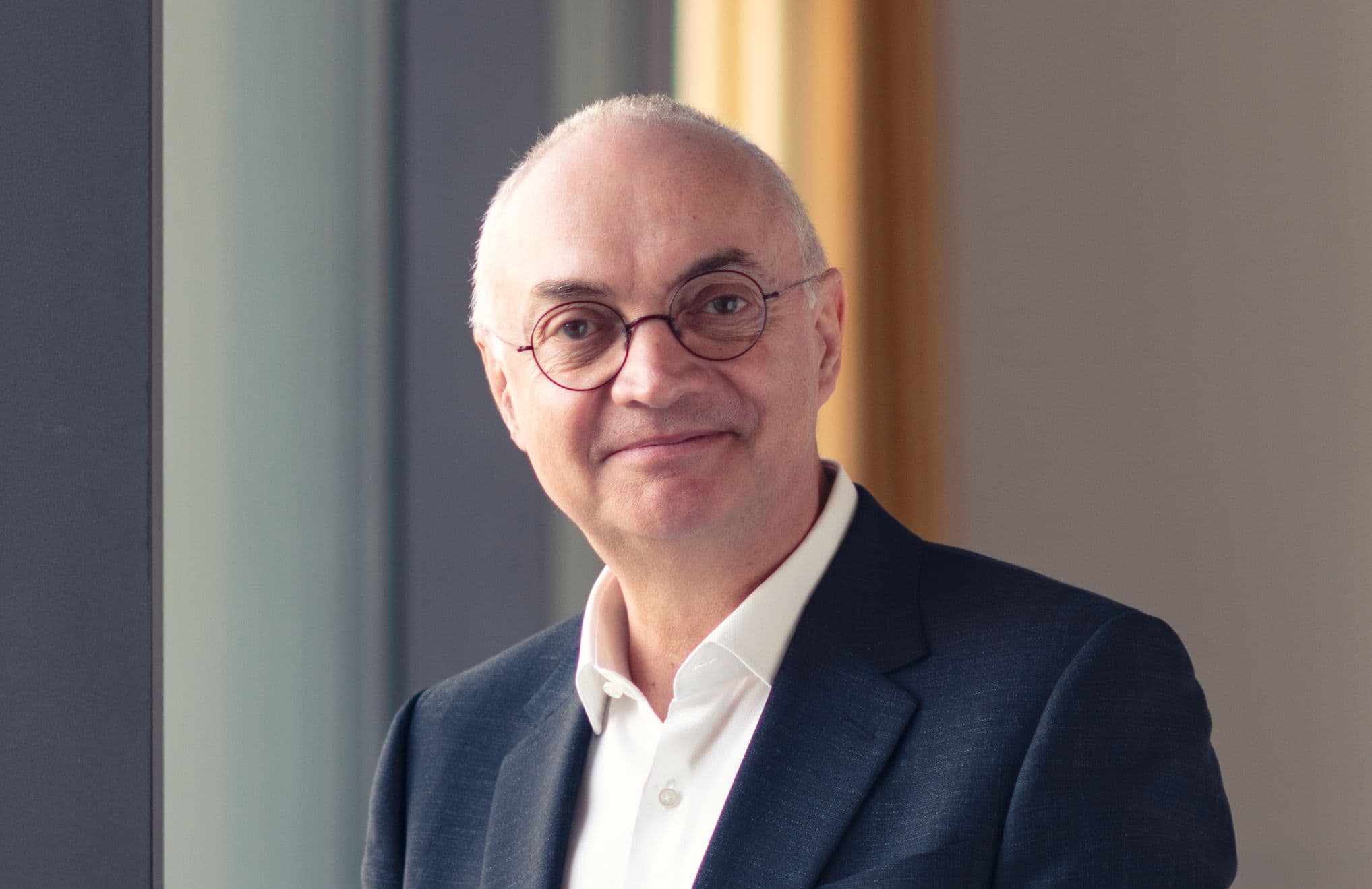 Luc%20Van%20den%20hove Portret van Luc Van den hove in een donker pak en met een bril, binnen staand bij een raam
