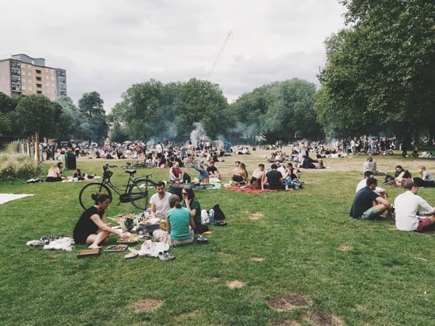 luchtkwaliteit-meten-park Mensen die picknicken en ontspannen in een stadspark met rook die boven het gras drijft