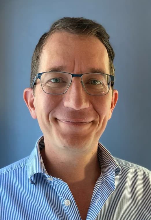 Mathijs%20Zandbergen Headshot of Mathijs Zandbergen wearing glasses and a blue striped shirt against a blue background.