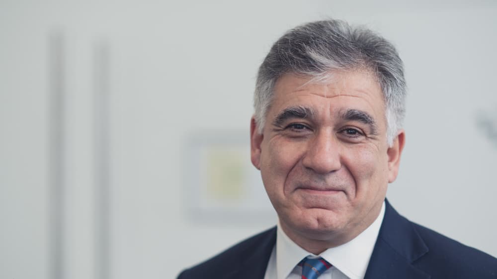 Max-Mirgoli Portrait of Max Mirgoli in a suit and tie against a blurred office background