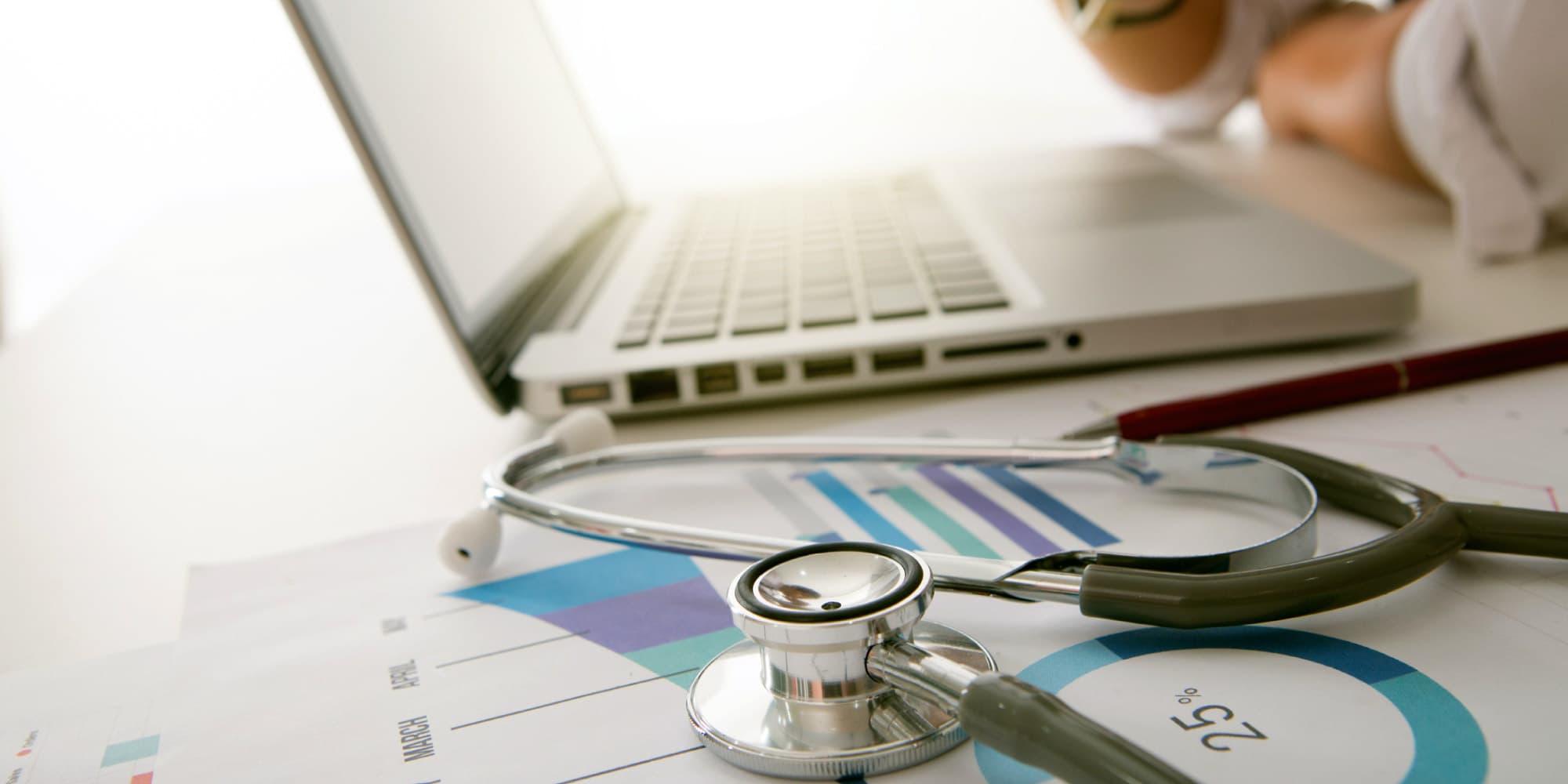 medical-dataa Stethoscope on medical charts beside a laptop, suggesting digital healthcare data analysis.