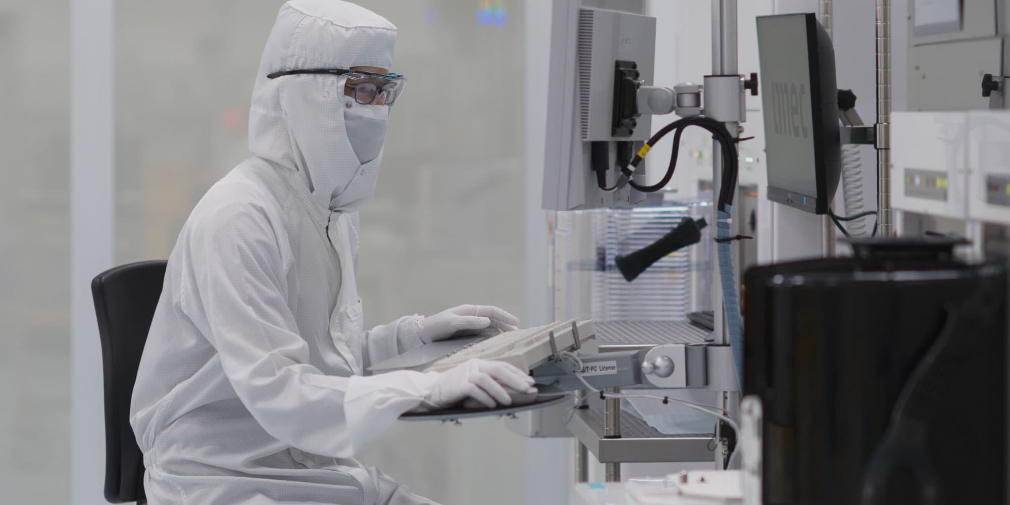 memory-storage-header Researcher in a cleanroom suit working at a computer beside lab equipment