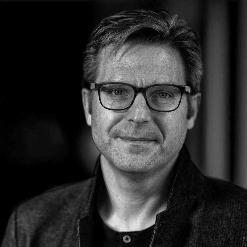 Michael%20Peeters%20zwart%20wit Portrait of Michael Peeters wearing glasses, shown in black and white.