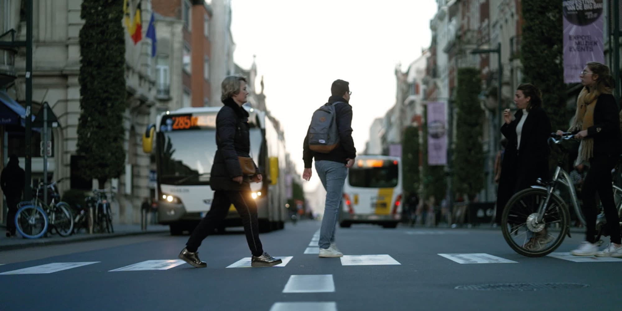 mobiliteit Voetgangers en fietsers steken een stadsstraat over met bussen op de achtergrond
