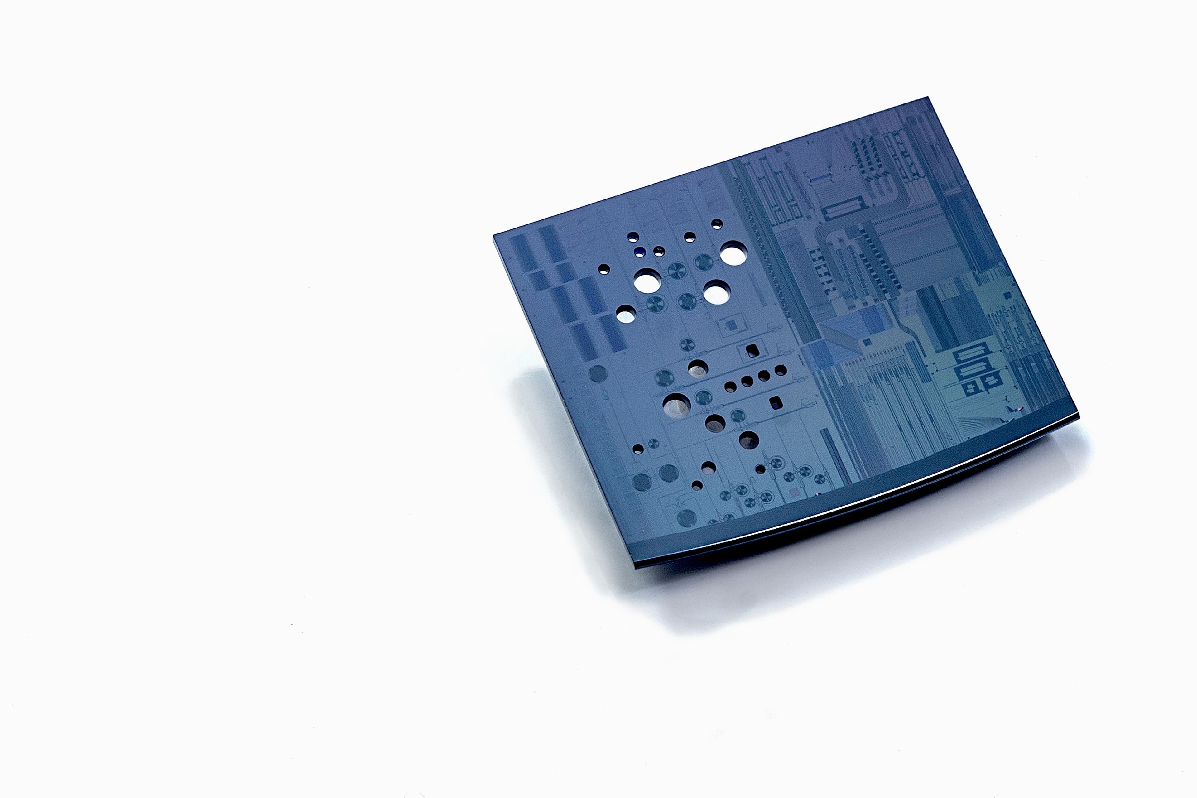MOMS_1 Blue micro-optomechanical sensor chip with multiple circular holes on a white background