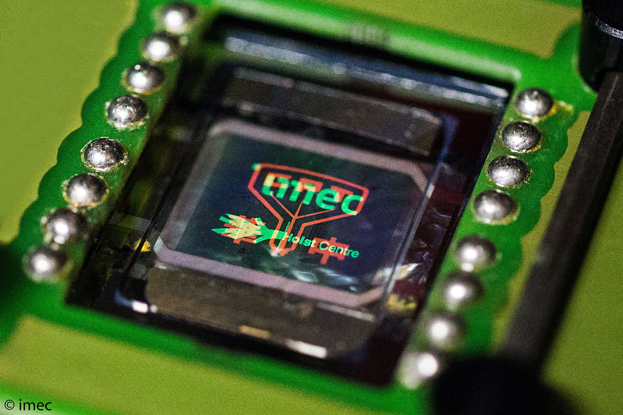 multicolor-oled-display001_0_0 Close-up of a multicolor OLED display module on a green circuit board with imec and Holst Centre branding