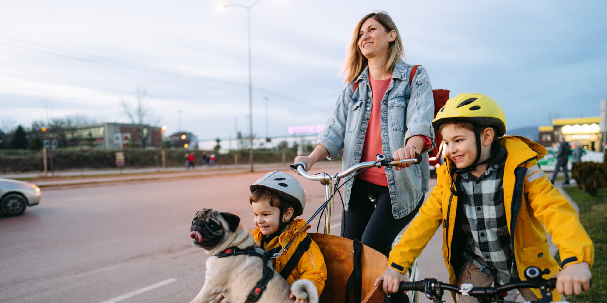 Naar-een-betere-fietservaring-in-de-EU-dankzij-data-spaces- Vrouw die een fiets voortduwt met twee kinderen met helm en een mopshond in een fietskar.