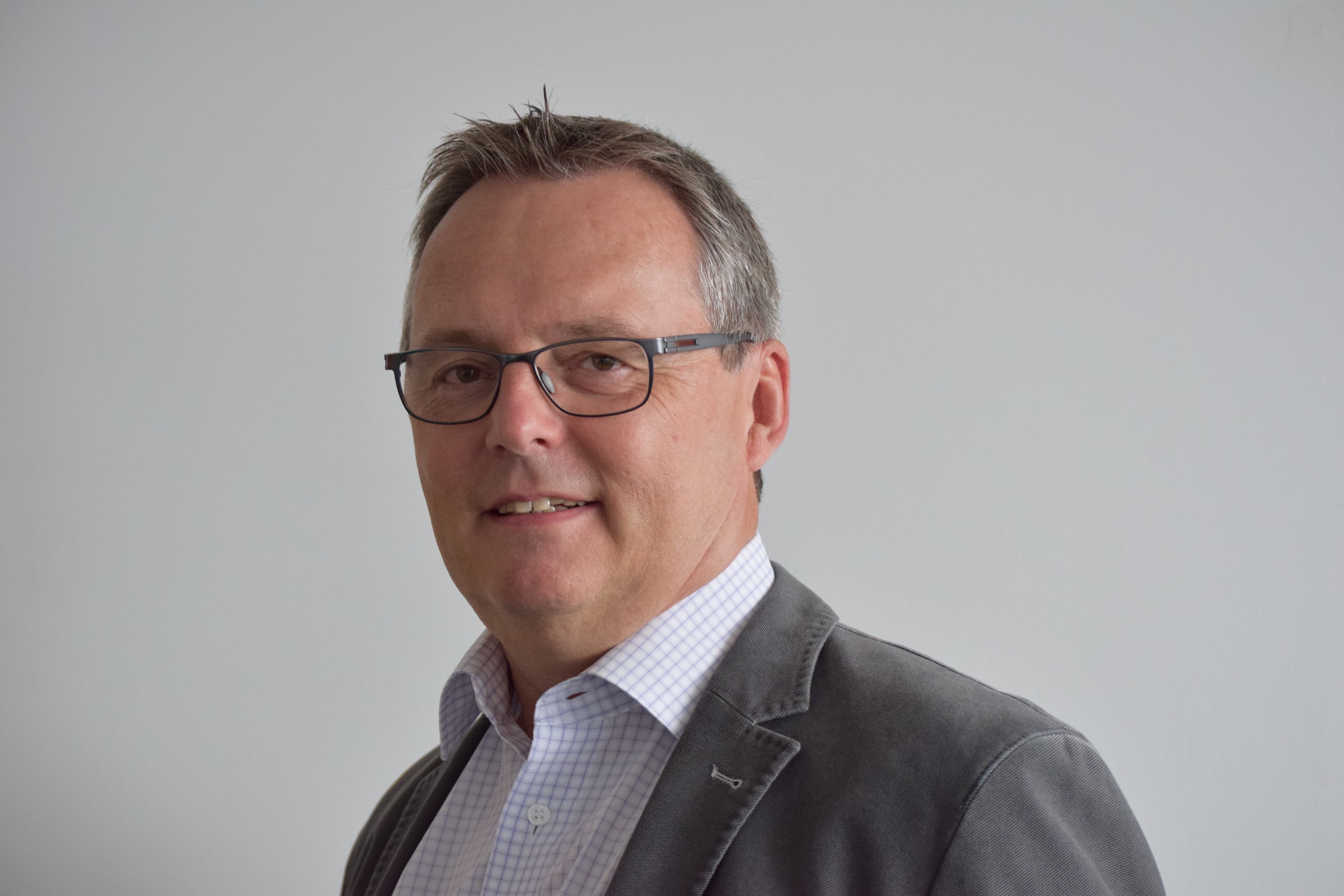 Norbert_Haberland_1 Headshot of Norbert Haberland wearing glasses and a gray blazer against a plain background