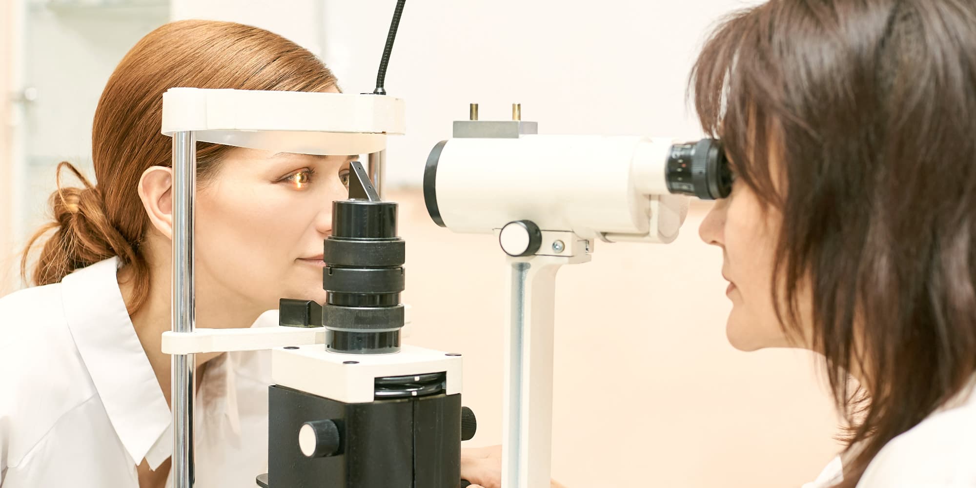 OCT-Technology Two women using an eye examination device with an illuminated view of the eye