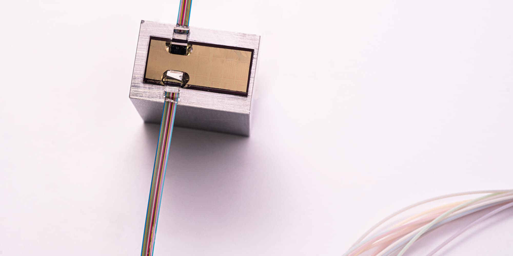 OMUS Compact optomechanical ultrasound sensor with rainbow-colored fiber cables attached to a metal module
