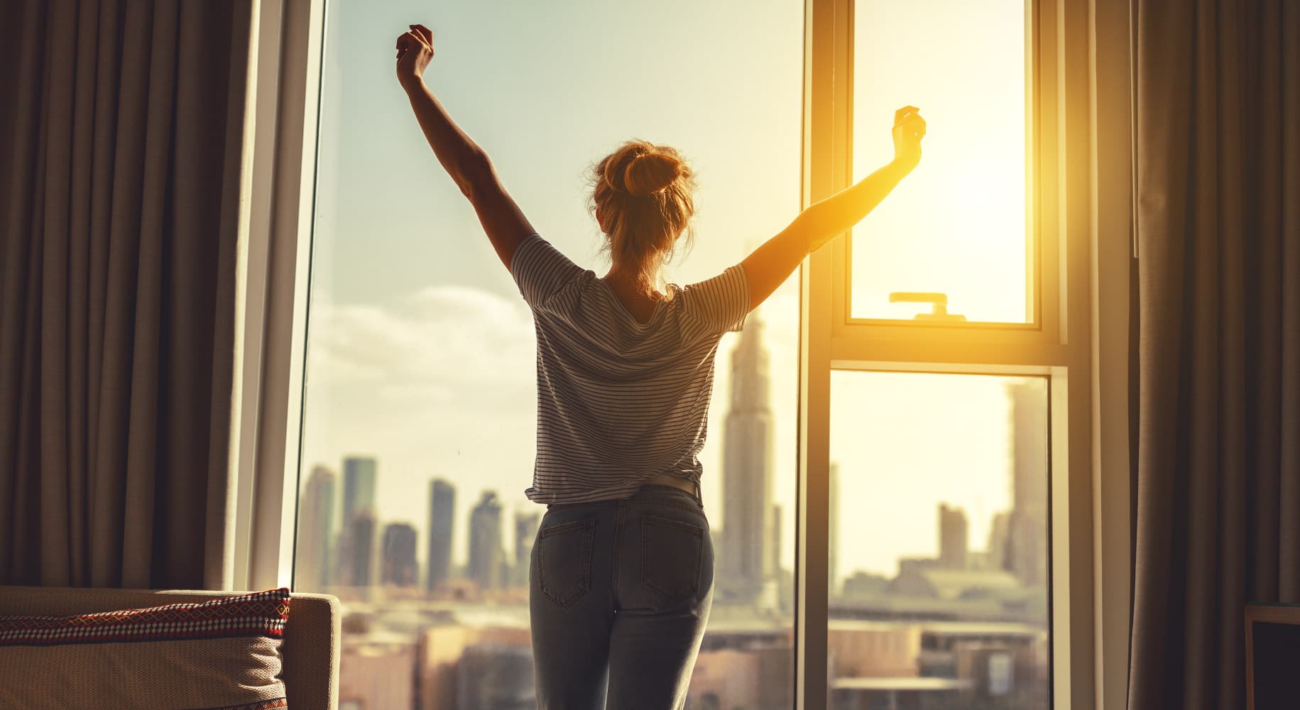 Onera-sleep-diagnostics_1 Woman stretching beside a window in morning light, overlooking a city skyline