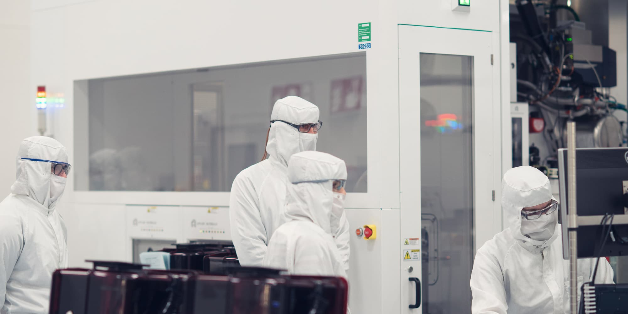 Optical-interconnects Researchers in cleanroom suits working beside semiconductor equipment in a lab